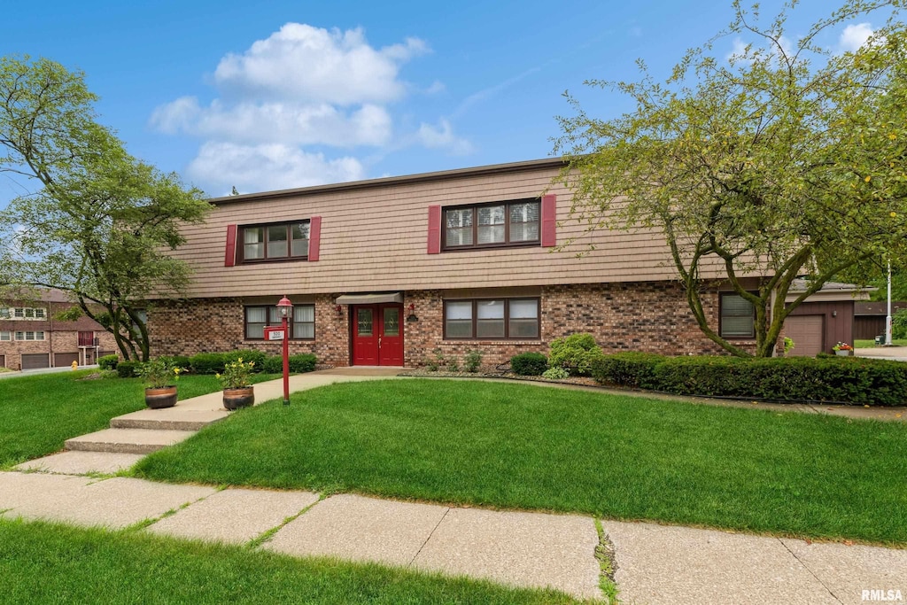 townhome / multi-family property with brick siding and a front lawn