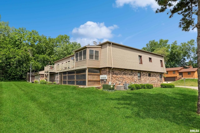 view of side of home featuring cooling unit, a sunroom, brick siding, and a lawn