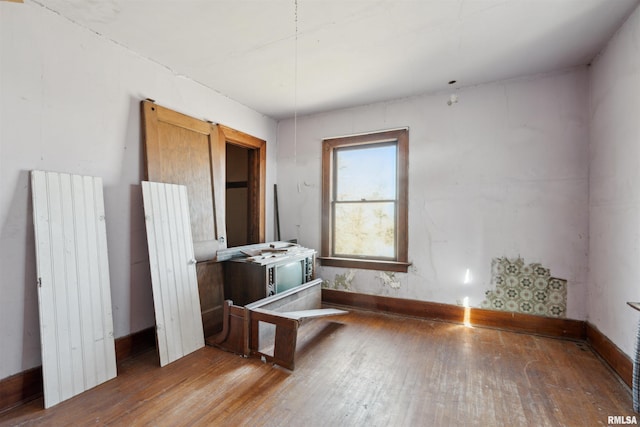 spare room featuring radiator heating unit, baseboards, and wood-type flooring
