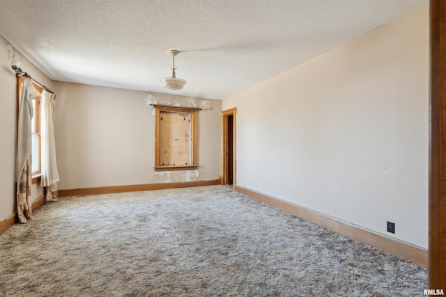 spare room with baseboards, carpet floors, and a textured ceiling