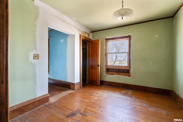 spare room with baseboards, wood-type flooring, and ornamental molding