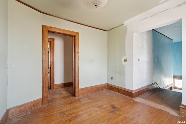 unfurnished room featuring baseboards, hardwood / wood-style floors, and crown molding