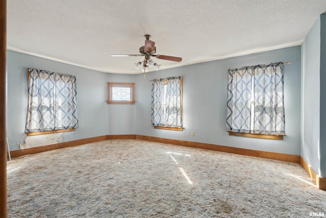 carpeted empty room with ceiling fan, baseboards, and a textured ceiling