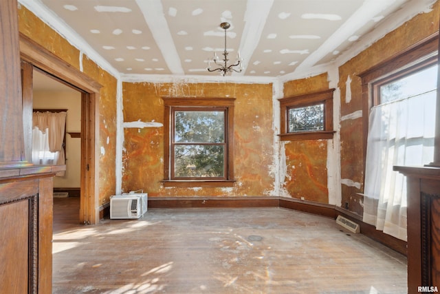 spare room featuring an AC wall unit, plenty of natural light, an inviting chandelier, and crown molding