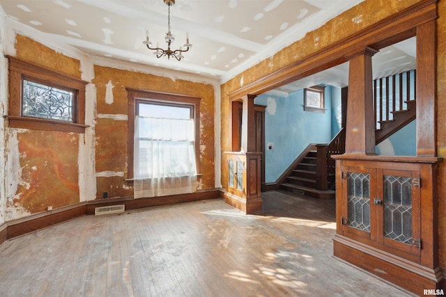 interior space featuring baseboards, visible vents, stairs, hardwood / wood-style flooring, and a chandelier