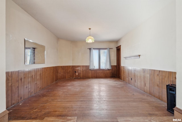spare room with wainscoting, wood walls, and hardwood / wood-style floors