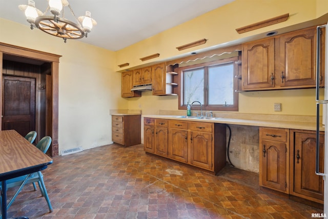 kitchen with brown cabinetry, visible vents, an inviting chandelier, and a sink