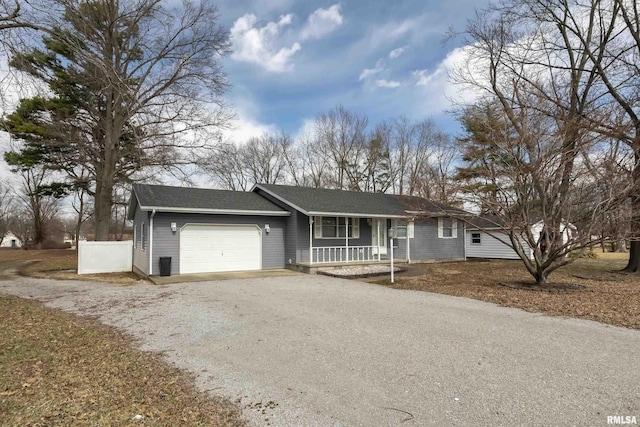 single story home with a porch, an attached garage, fence, and gravel driveway