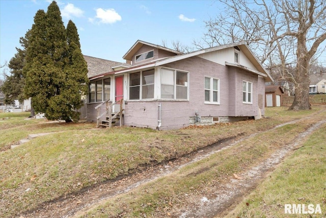 bungalow-style house featuring entry steps, brick siding, and a front yard