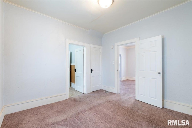 carpeted empty room featuring crown molding and baseboards