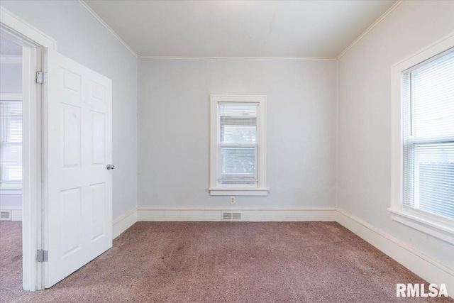 carpeted empty room with ornamental molding, visible vents, plenty of natural light, and baseboards