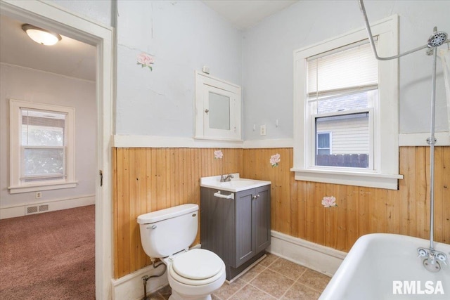 bathroom featuring a wainscoted wall, visible vents, toilet, wood walls, and a freestanding tub