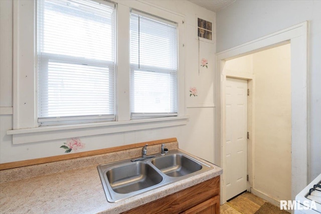 kitchen featuring brown cabinets, visible vents, light countertops, and a sink