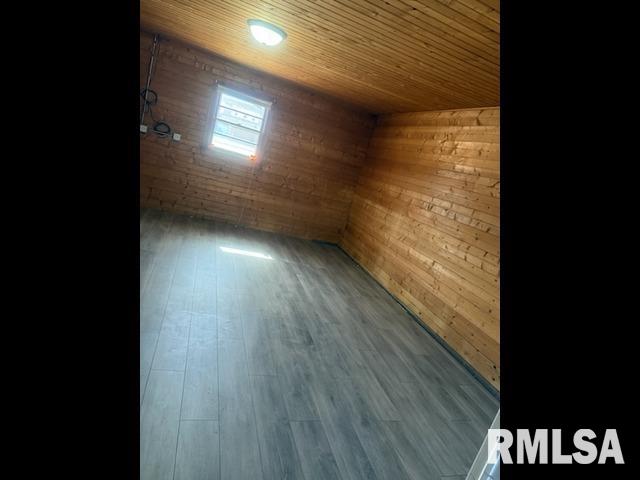 empty room with wood walls, wooden ceiling, and wood finished floors