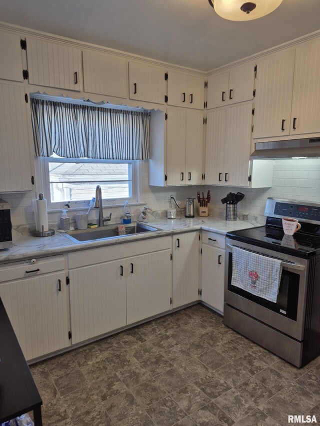 kitchen featuring tasteful backsplash, under cabinet range hood, light countertops, stainless steel range with electric stovetop, and a sink