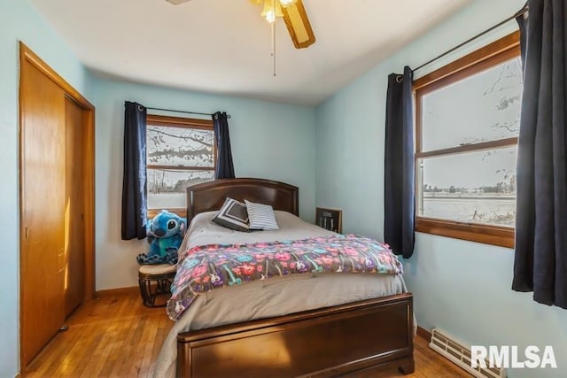 bedroom with ceiling fan, a closet, wood finished floors, and baseboards