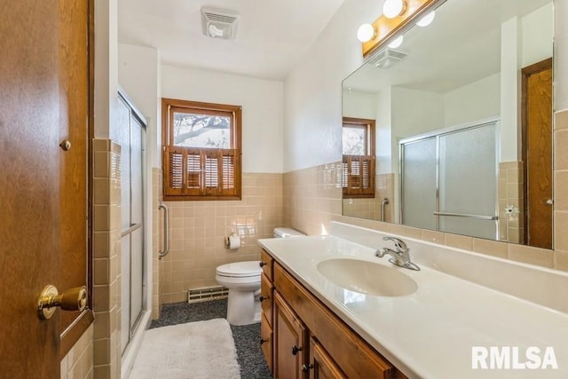 bathroom with a stall shower, vanity, visible vents, and tile walls