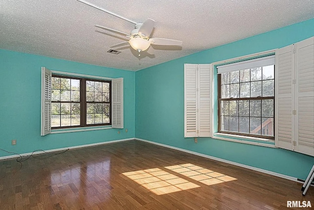 empty room featuring visible vents, a textured ceiling, wood finished floors, baseboards, and ceiling fan