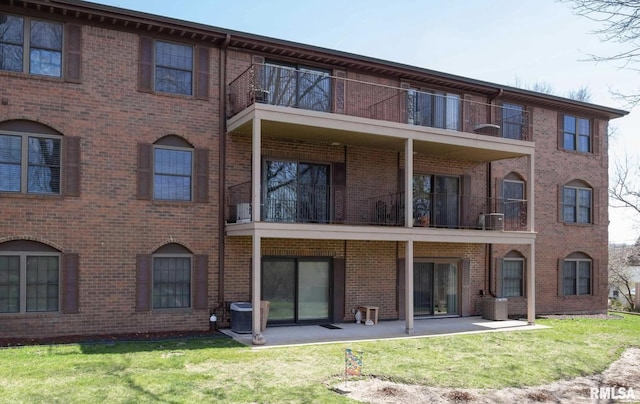 back of property with brick siding, cooling unit, and a yard