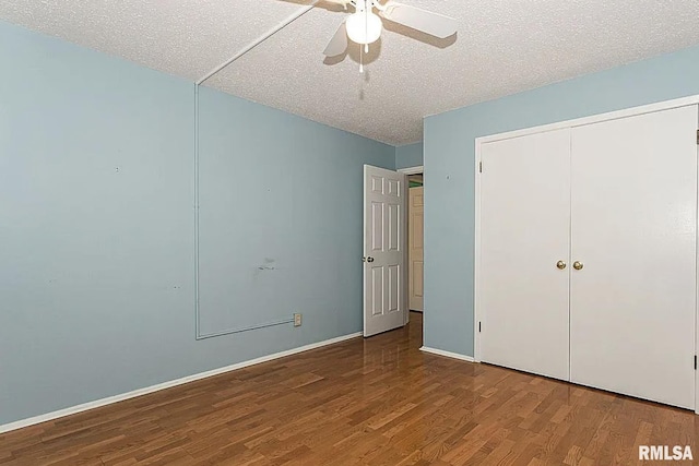 unfurnished bedroom featuring a ceiling fan, a textured ceiling, wood finished floors, a closet, and baseboards