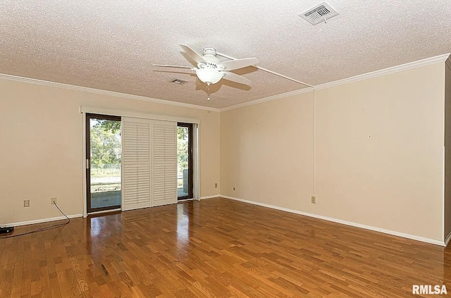 empty room with visible vents, a textured ceiling, crown molding, and wood finished floors