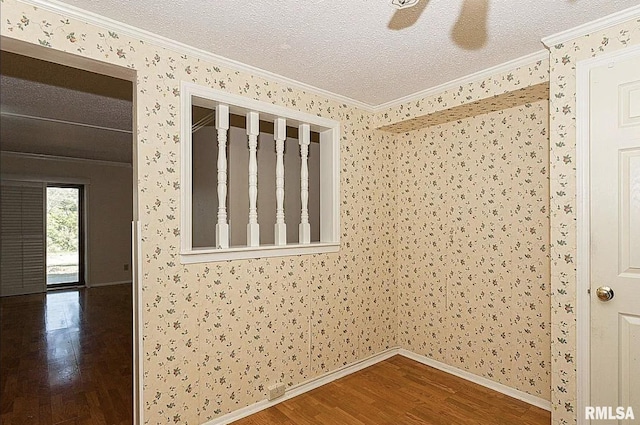 spare room featuring baseboards, a textured ceiling, wood finished floors, and crown molding