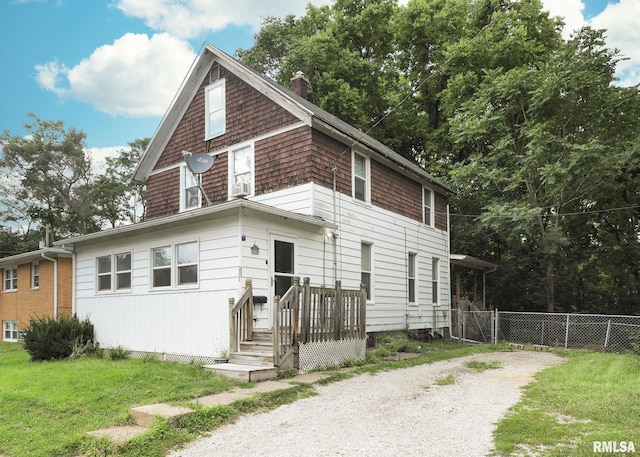 view of front of home with driveway, a front yard, fence, and a chimney