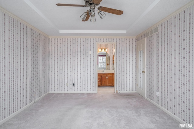 spare room featuring a raised ceiling, light colored carpet, and wallpapered walls