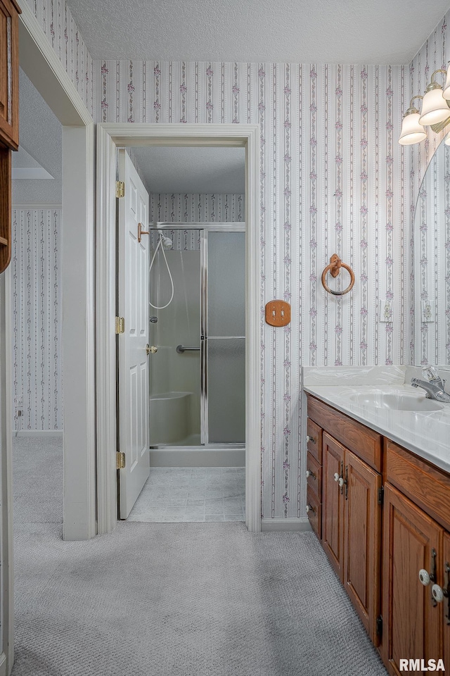 bathroom featuring a textured ceiling, a stall shower, vanity, and wallpapered walls