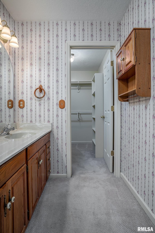 bathroom featuring a textured ceiling, baseboards, and wallpapered walls