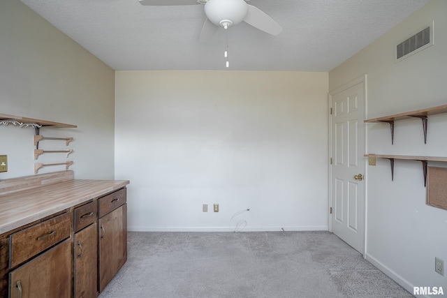 interior space with a textured ceiling, ceiling fan, light colored carpet, visible vents, and open shelves