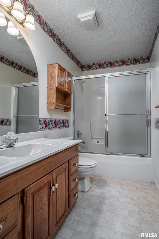 full bath featuring a textured ceiling, toilet, shower / bath combination with glass door, and vanity