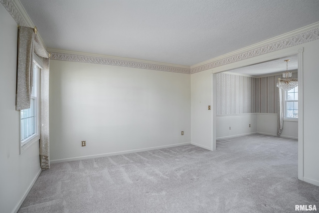 unfurnished room featuring carpet, crown molding, an inviting chandelier, a textured ceiling, and baseboards