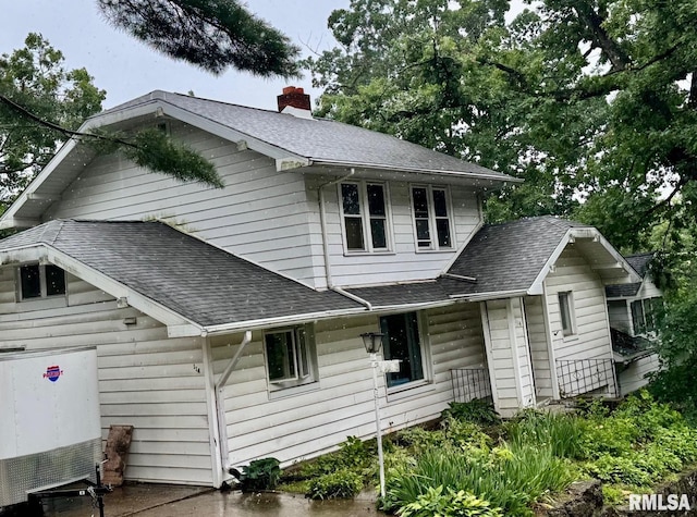 view of front of home featuring a chimney and roof with shingles