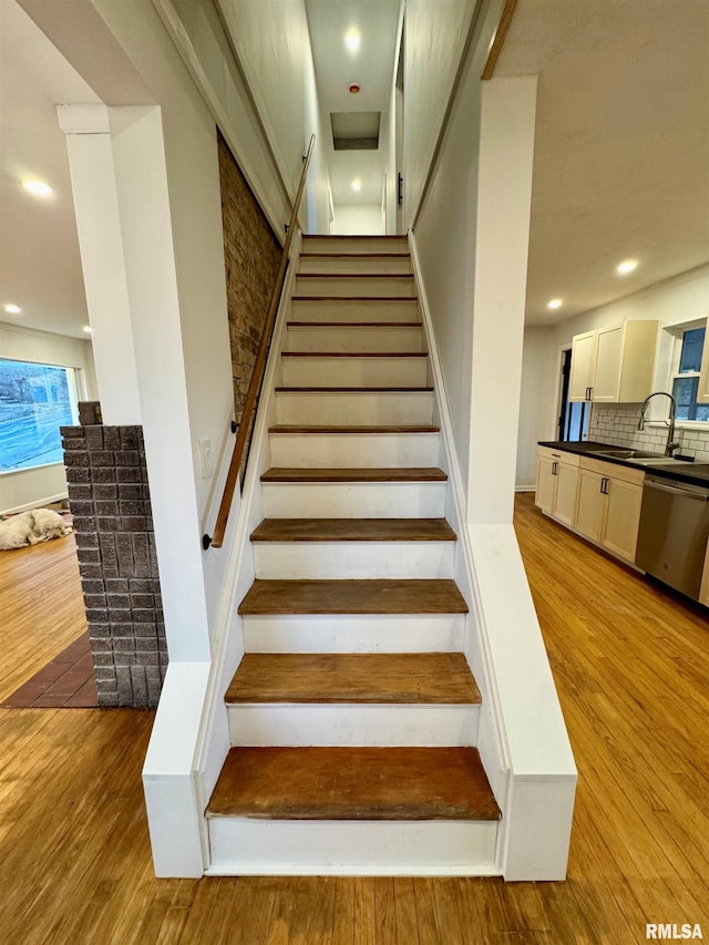 stairway featuring wood finished floors and recessed lighting