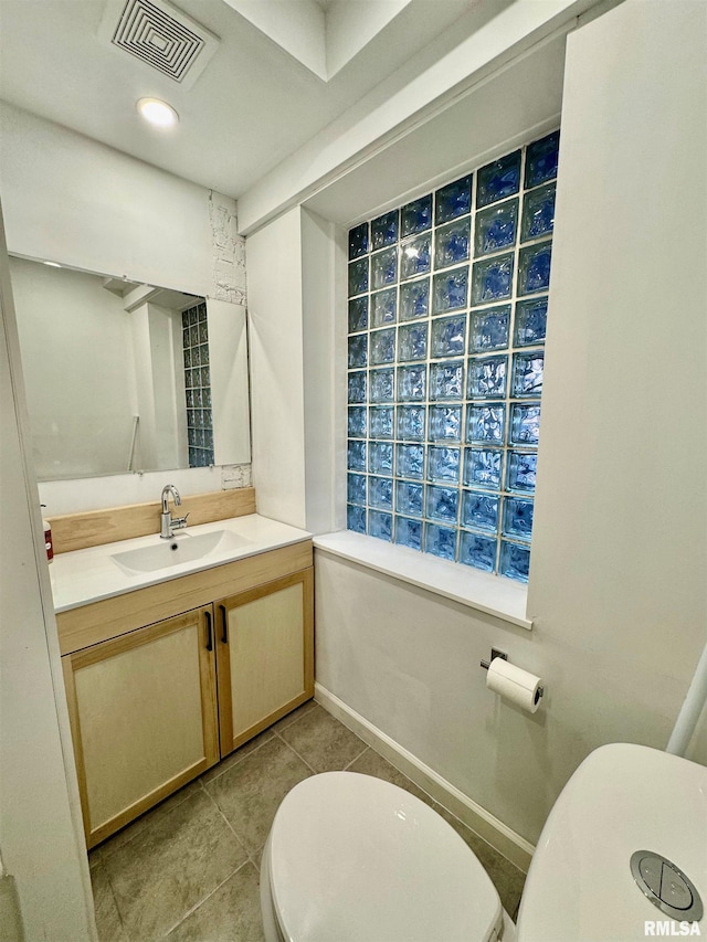 half bathroom with toilet, visible vents, baseboards, vanity, and tile patterned floors