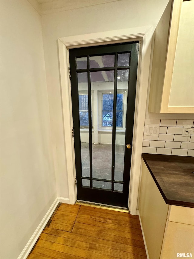 doorway with baseboards and wood finished floors