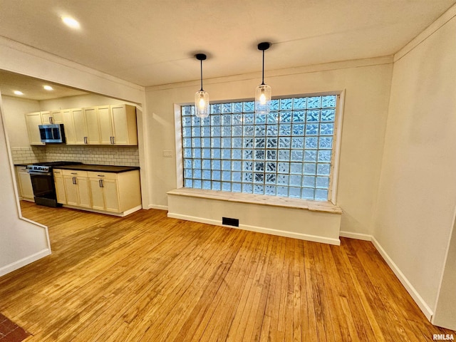 unfurnished dining area featuring ornamental molding, light wood-type flooring, and baseboards