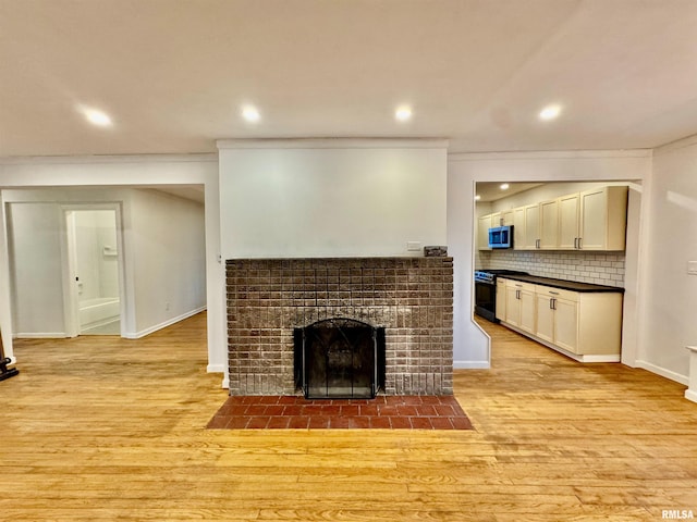 114 Dewhurst St, Savanna, IL 61074 - unfurnished living room featuring light wood finished floors, a tiled fireplace, recessed lighting, baseboards, and ornamental molding
