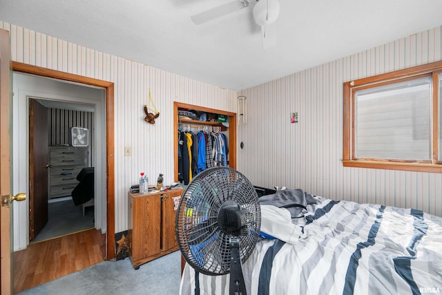 bedroom featuring ceiling fan, a closet, and wallpapered walls