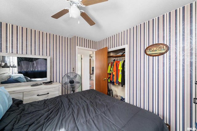 bedroom featuring a textured ceiling, a ceiling fan, and wallpapered walls