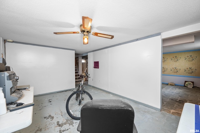 workout room with ceiling fan and a textured ceiling