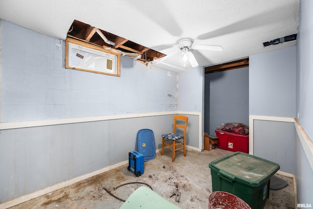 playroom featuring a textured ceiling, concrete floors, concrete block wall, and a ceiling fan