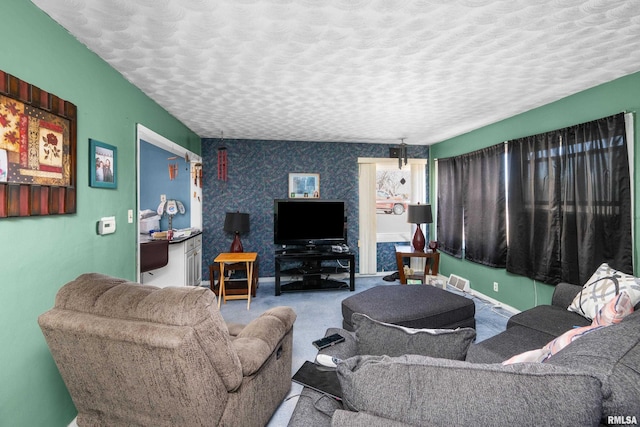 living area with a textured ceiling, carpet, and baseboards