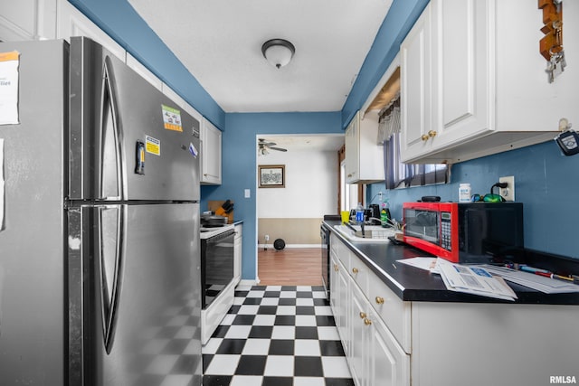 kitchen with tile patterned floors, white cabinetry, white range with electric stovetop, freestanding refrigerator, and dark countertops