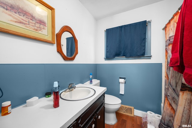 bathroom featuring visible vents, toilet, vanity, wood finished floors, and baseboards