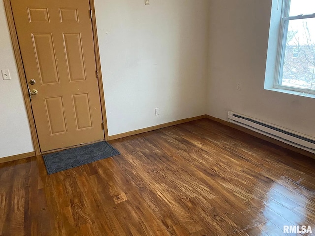 unfurnished room featuring a baseboard radiator, baseboards, and dark wood finished floors