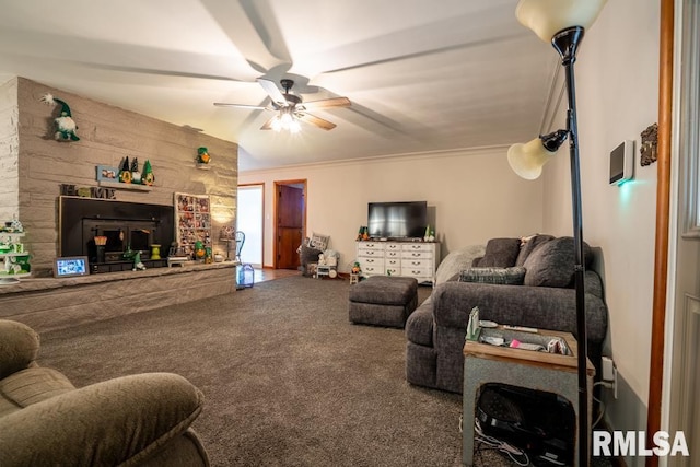 living area featuring a fireplace with raised hearth, ornamental molding, carpet, and a ceiling fan