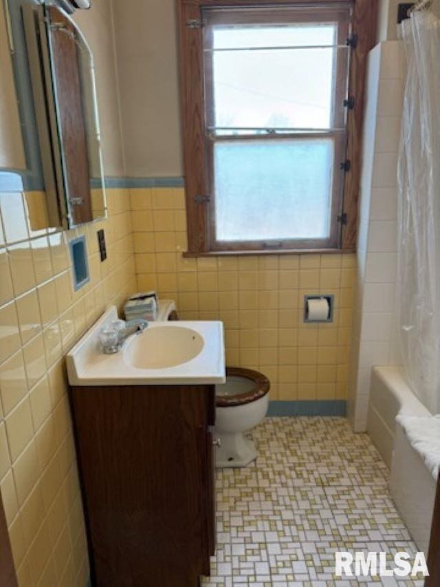 full bathroom with tile walls, plenty of natural light, vanity, and toilet