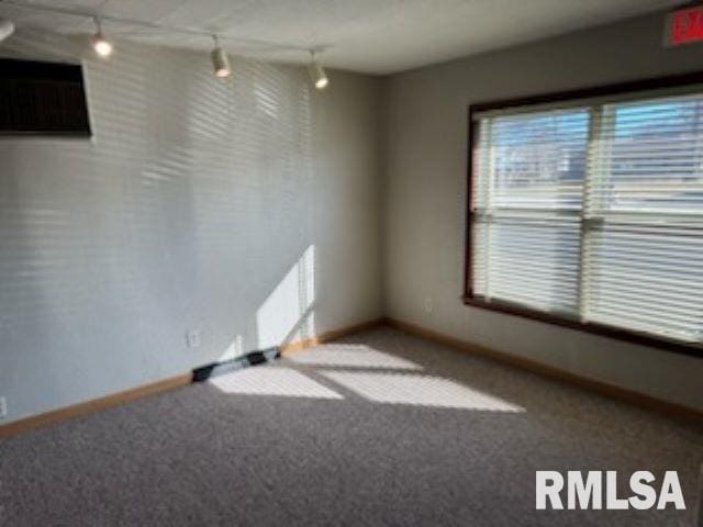 carpeted empty room with track lighting and baseboards